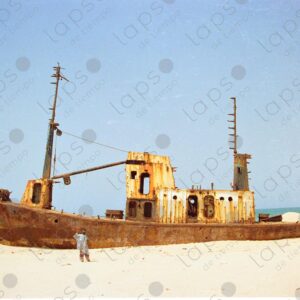 Abandoned boat on Saint-Louis beach and Senegalese man