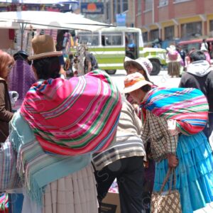 Cholita carries a cart of merchandise