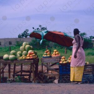 Woman selling fruit seen from a moving car