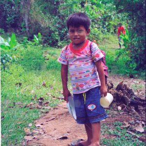 A boy with a backpack goes to school along the jungle path