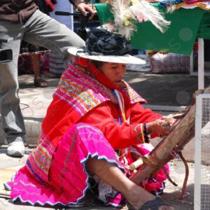 A woman in traditional indigenous attire weaving on a loom 2