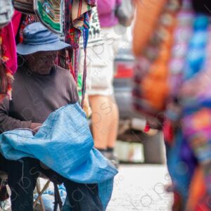 An old man repairs a sack of potatoes