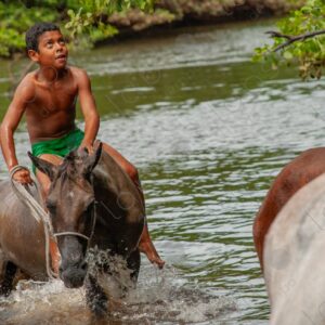 Boy coming out of the river riding a horse 2