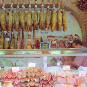 Display case with sausages and hams hanging in the background, Madrid