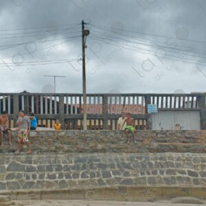 Group of children sitting on beach retaining wall 3
