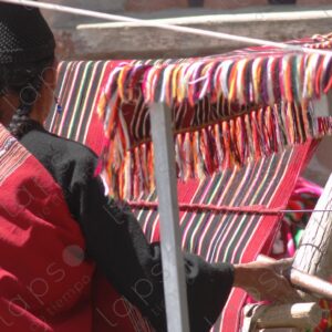 Indigenous woman working on a red loom with lines 4
