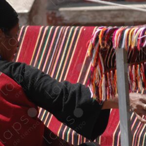 Indigenous woman working on a red loom with lines 6