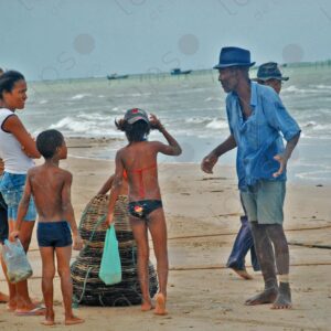 Man with cage baskets and women and children shopping on the seashore