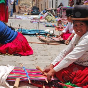 Several weavers on the floor with their looms weaving one smiling 1