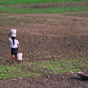 Woman carries a bucket on her head and another in her hand
