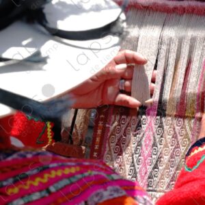 Woman in traditional indigenous attire weaving on a loom 1