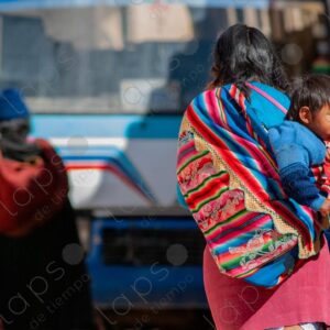 Woman walks carrying a child on her back in an aguayo 2