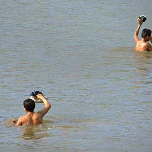 Young people cross the river with shoes in their hands 2