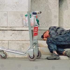 Homeless person sleeps with an airport trolley 1