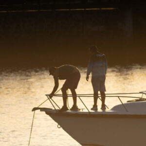 people at harbor with anchor in backlight 2