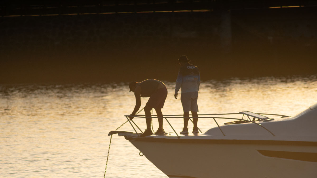 people at harbor with anchor in backlight 2