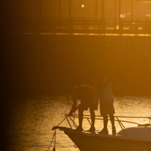 people at harbor with anchor in backlight 3