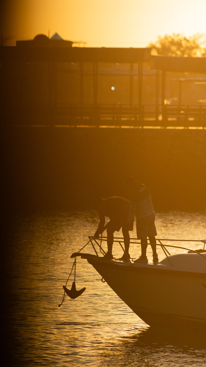 people at harbor with anchor in backlight 3
