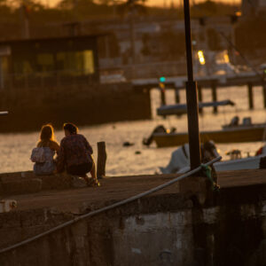 women sitting on pier at sunset 3